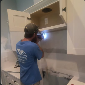 Dave in a Neighborly Handyman shirt working on kitchen cabinets